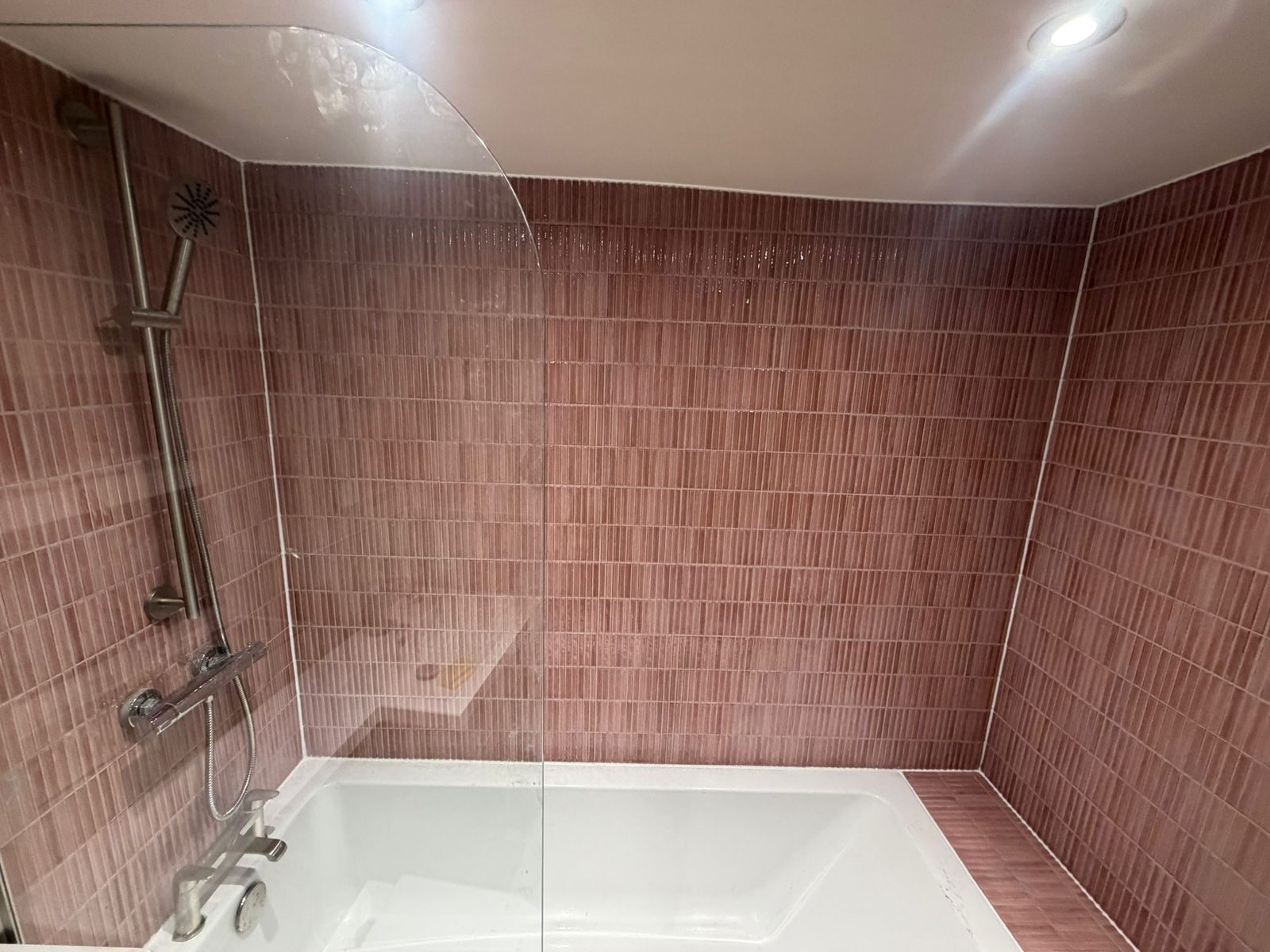Pink-tiled bath with grey vanity unit
