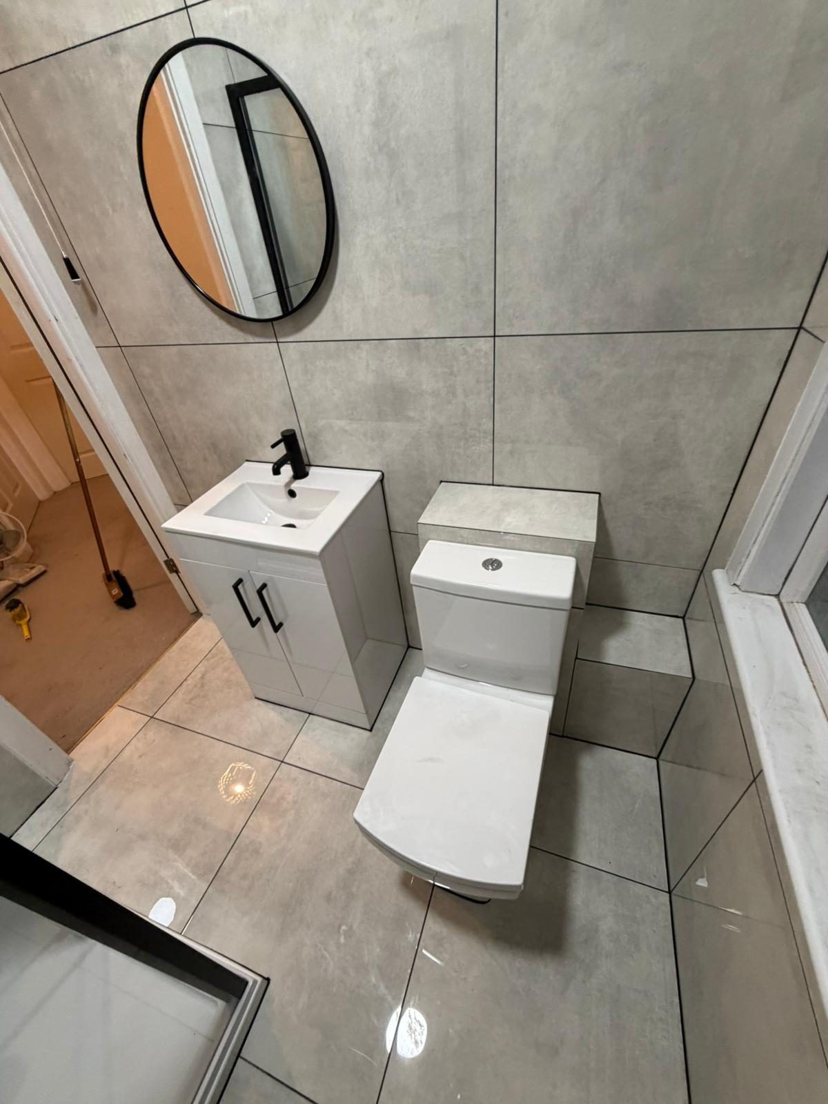 Grey-tiled cloakroom with round mirror
