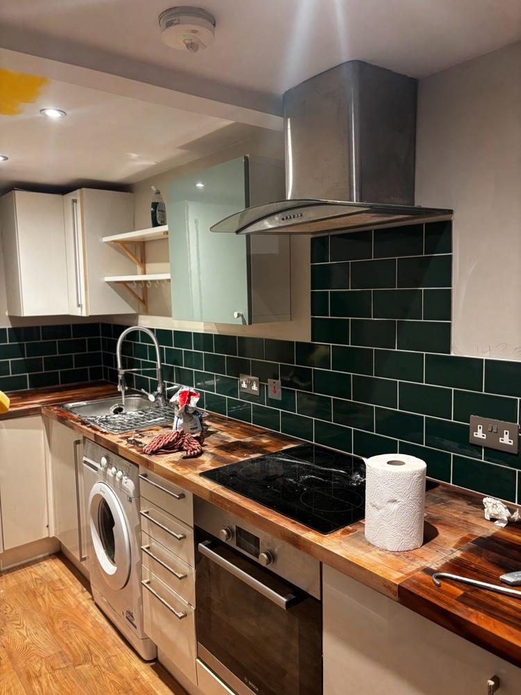 Kitchen with green metro tiles and white units