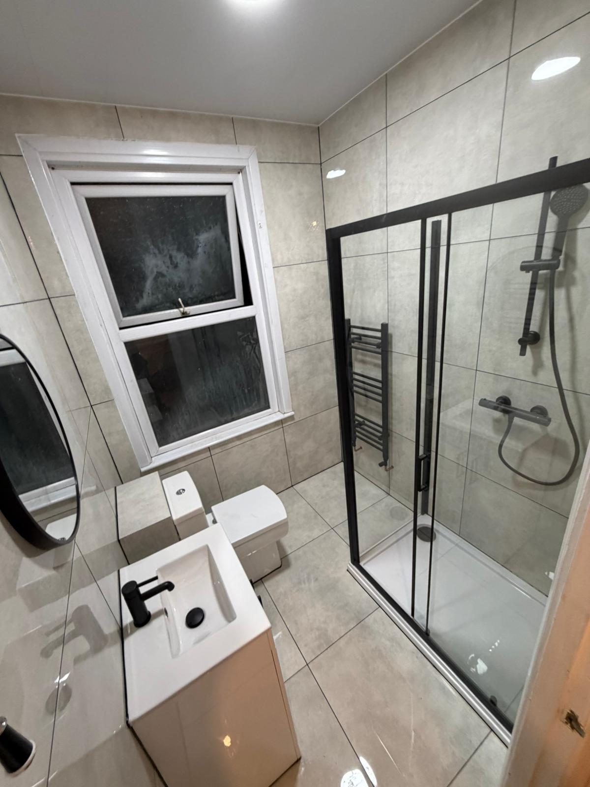 Grey-tiled shower with white suite
