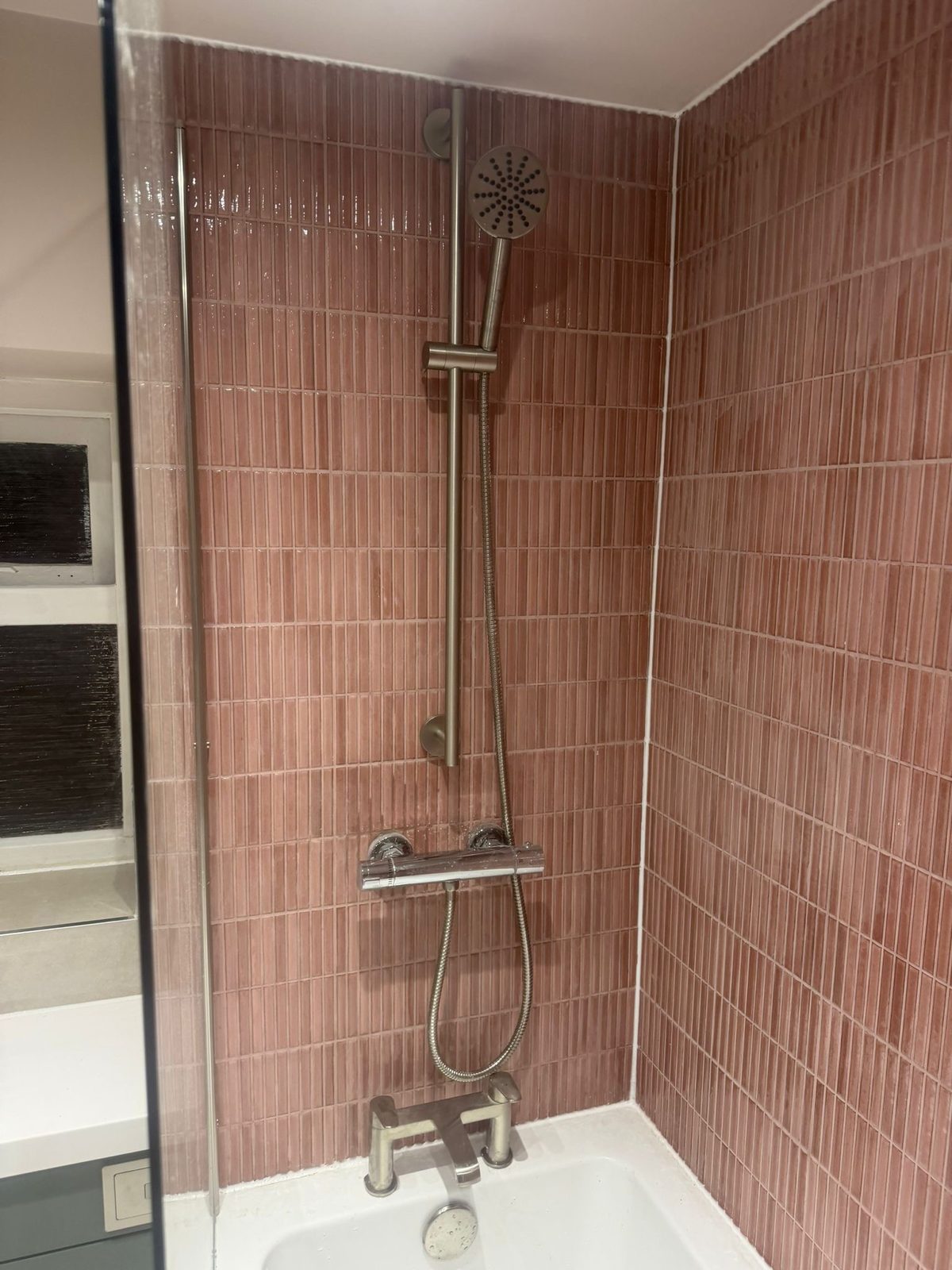 Pink-tiled bathroom with shower over bath