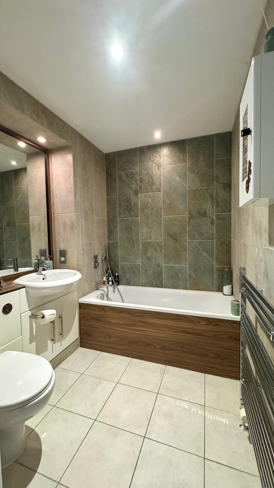 Completed bathroom renovation with green slate tiling and walnut bath panel