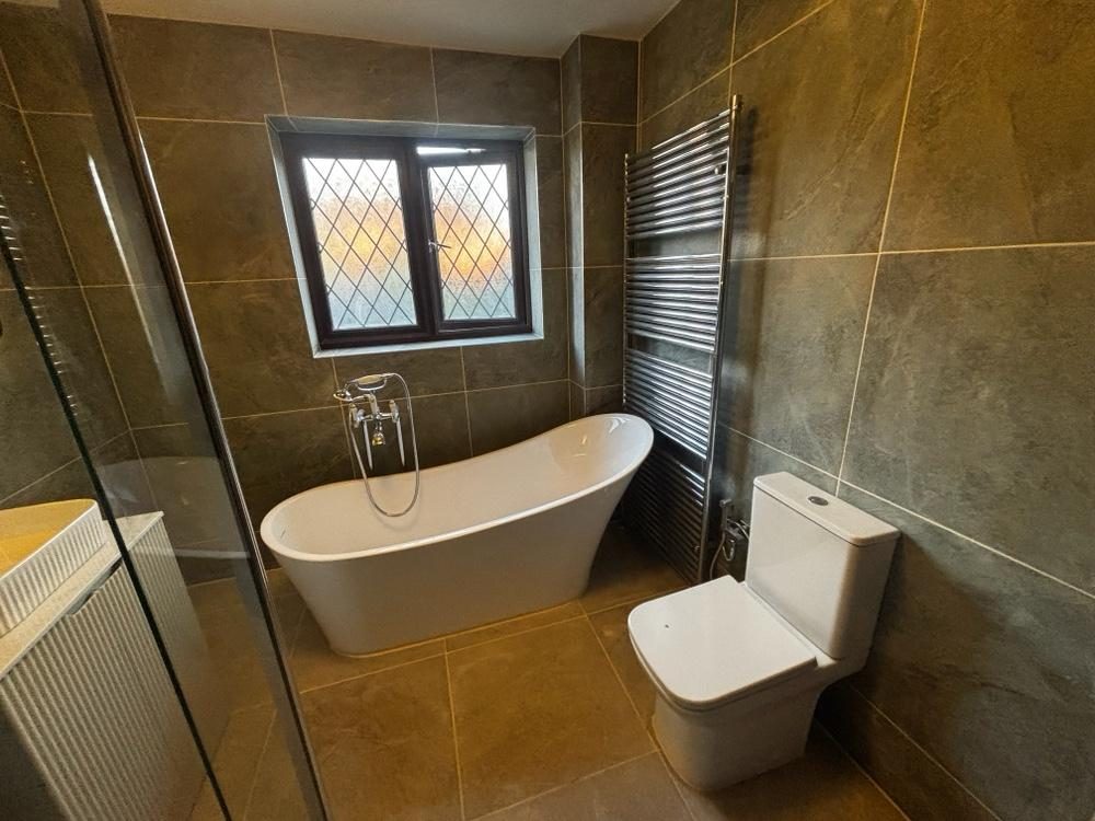 Slate bathroom with freestanding slipper bath and heated towel rail